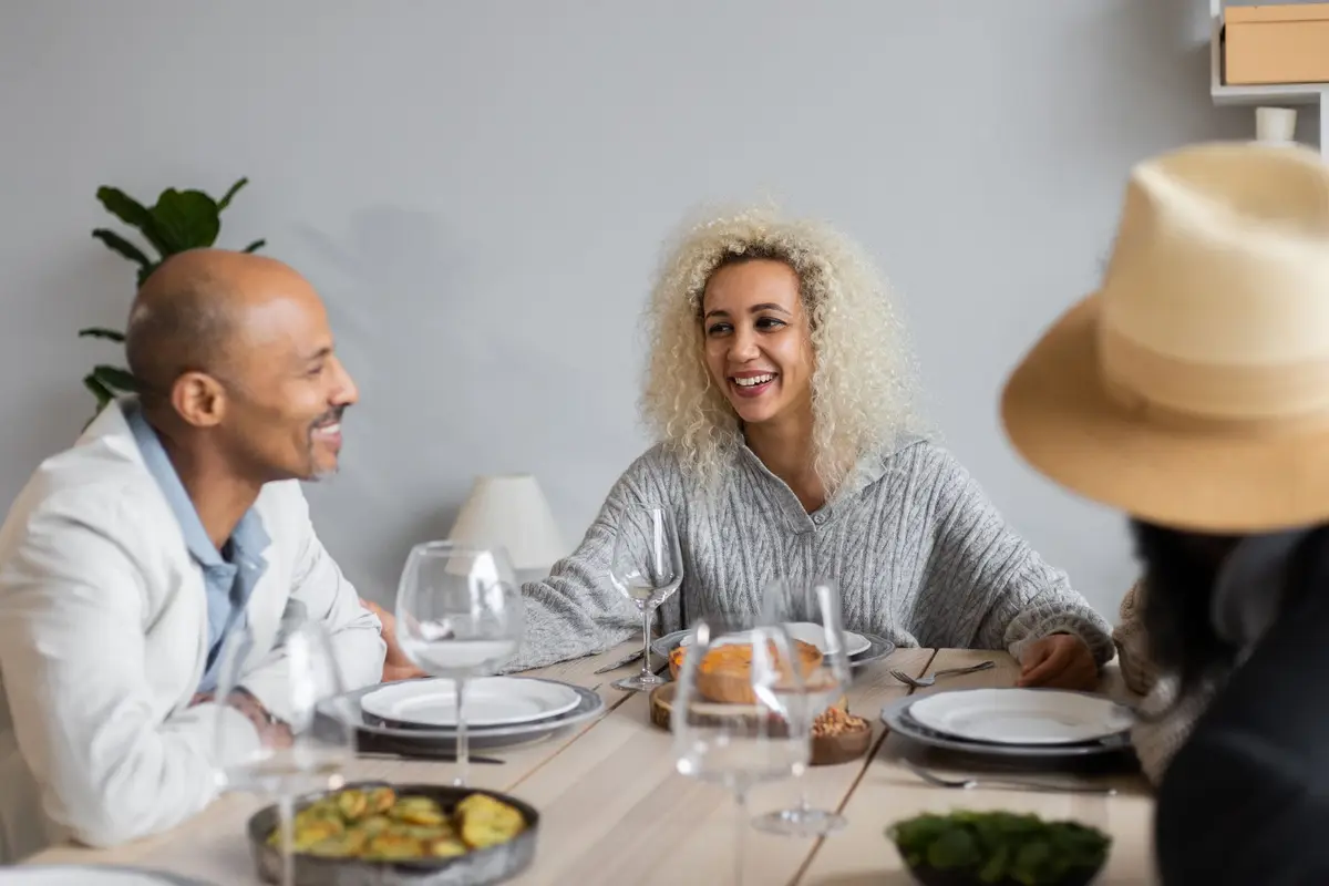 friends laughing together at a Thanksgiving dinner table, funny thanksgiving jokes for adults