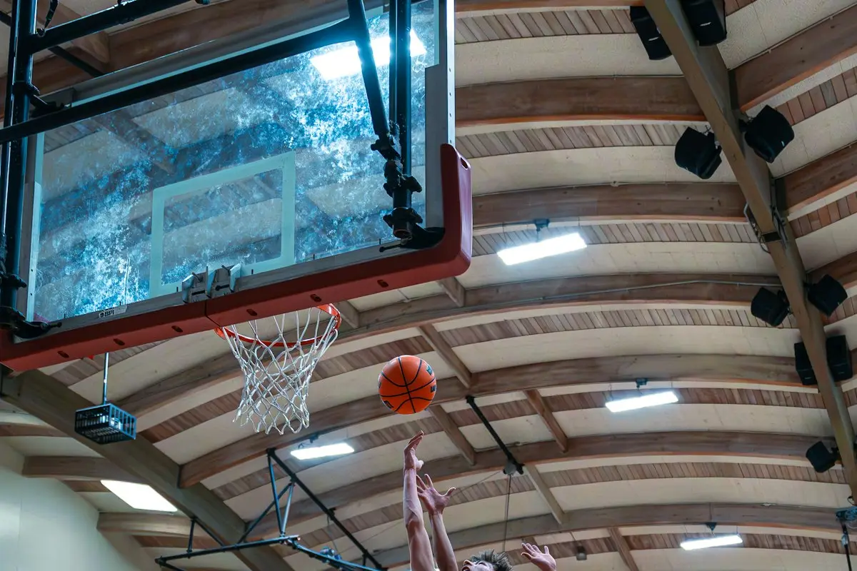 player rising to the hoop for a layup in a high school gym, image for basketball puns about dunks and layups
