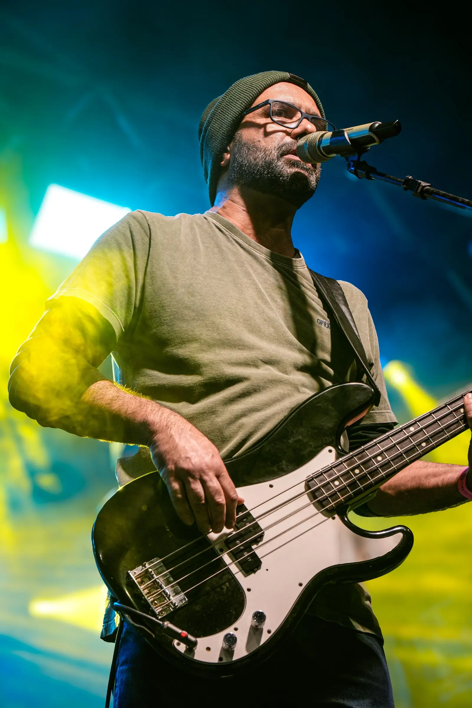 musician performing on stage with a bass guitar under vibrant lights, image for bass guitar captions