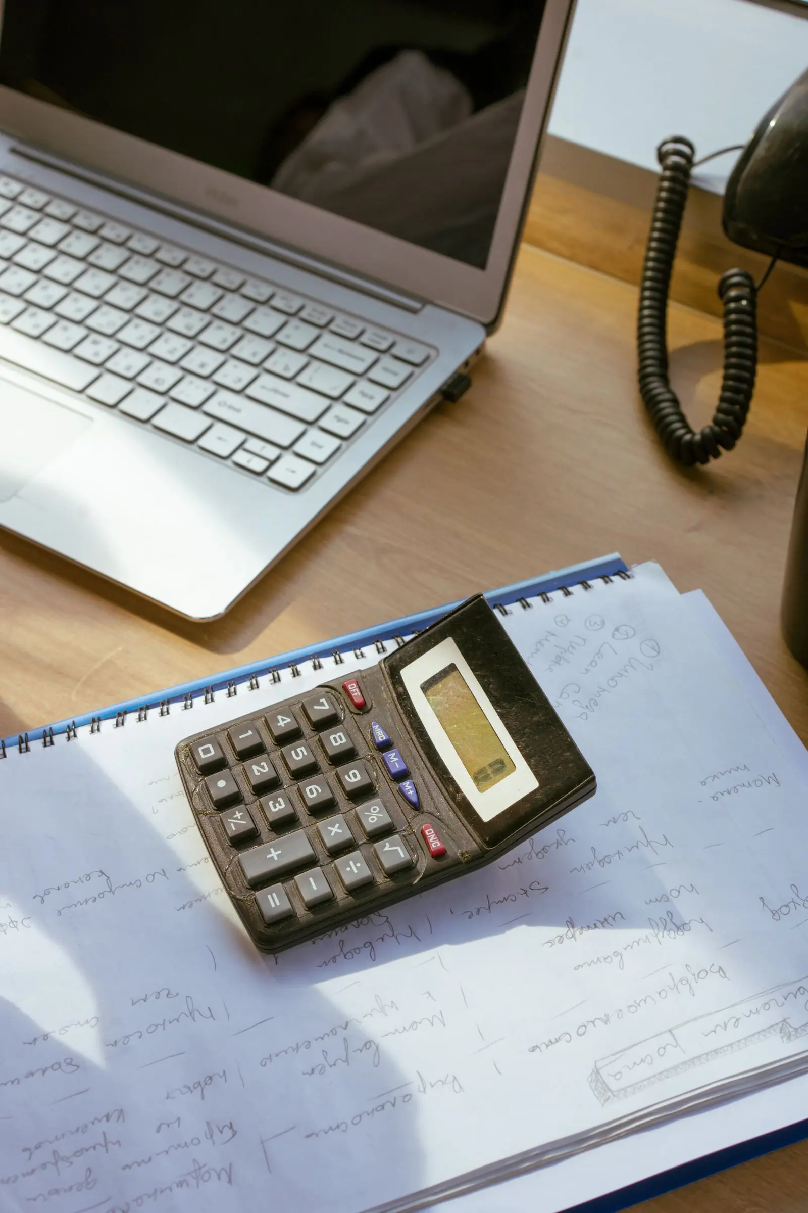 calculator resting on papers on a desk, image for algebra jokes and math puns for teachers