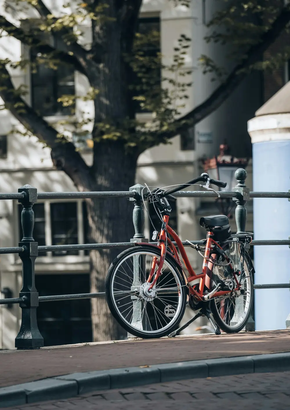 red city bicycle parked against a metal railing on a quiet street, image for short bicycle puns