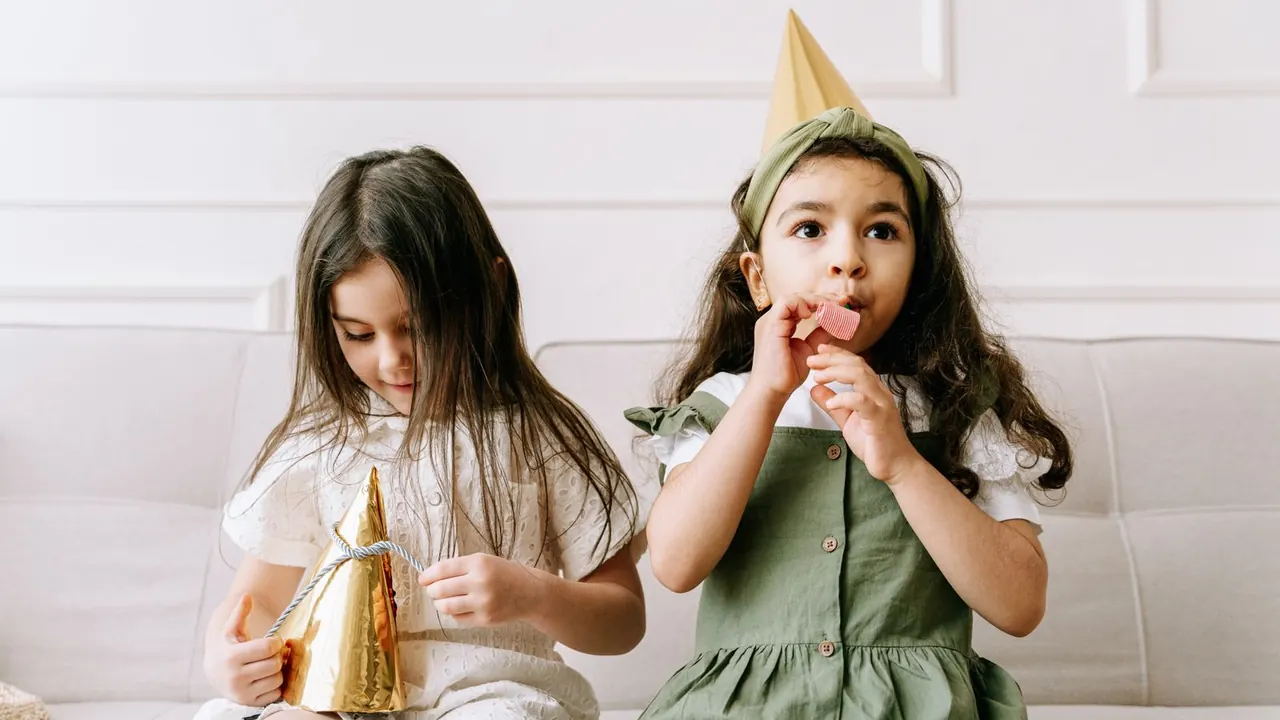 two girls wearing party hats at a birthday celebration, image for kid friendly birthday puns