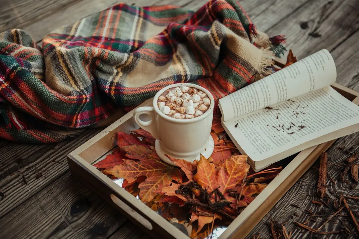 mug of coffee with marshmallow in front of an open book on a tray, image for reading and coffee puns