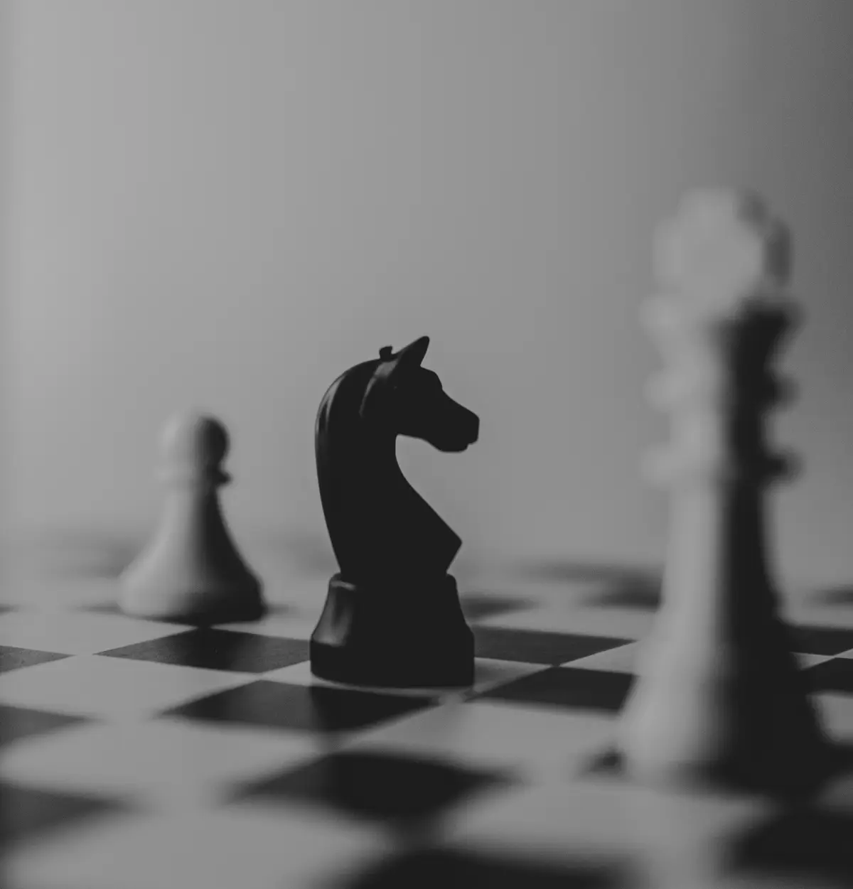 close-up of a black chess knight piece beside a rook, scene for chess piece puns
