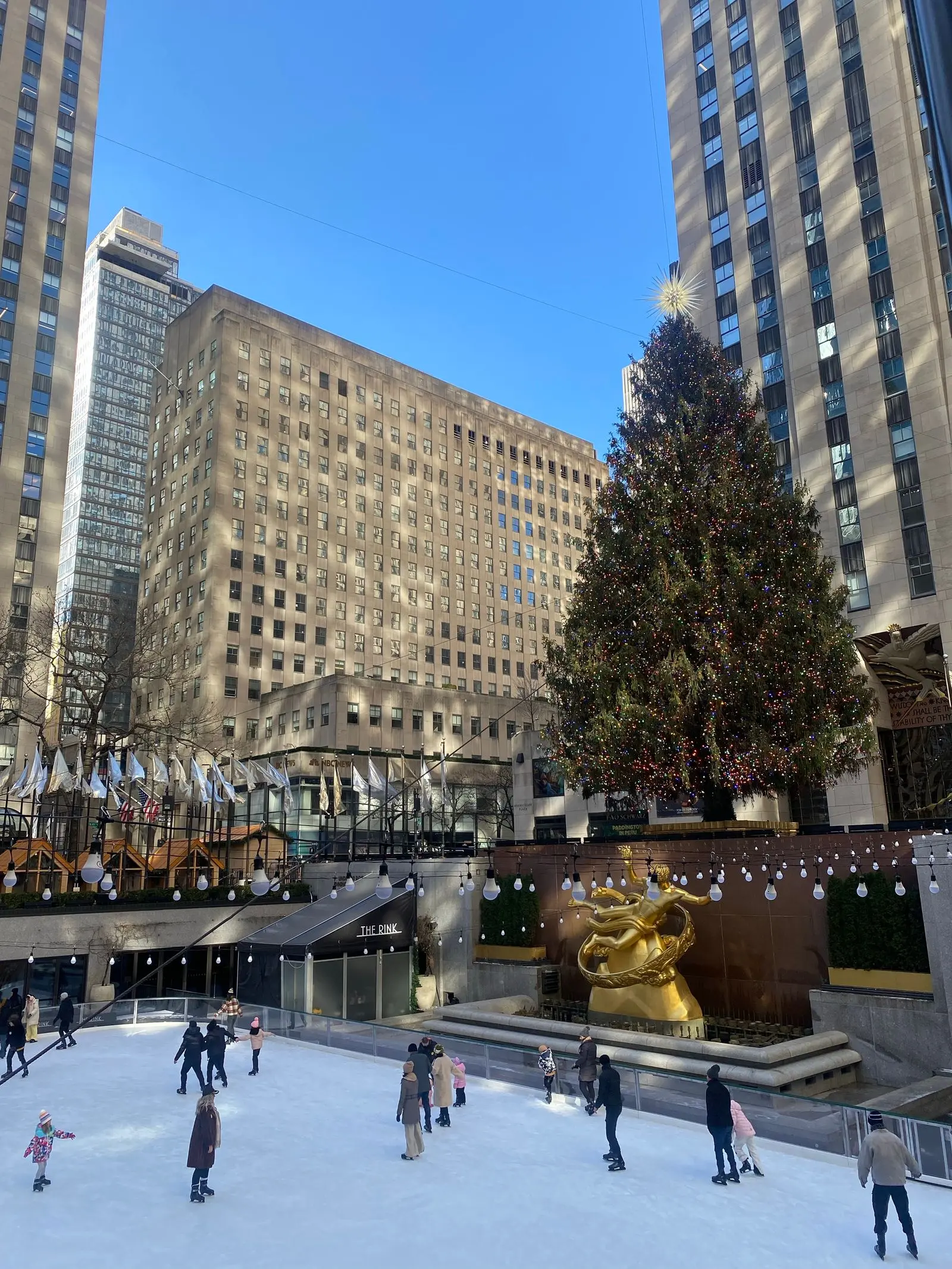 ice skaters at a festive rink with a Christmas tree, image for Santa and elf hockey puns