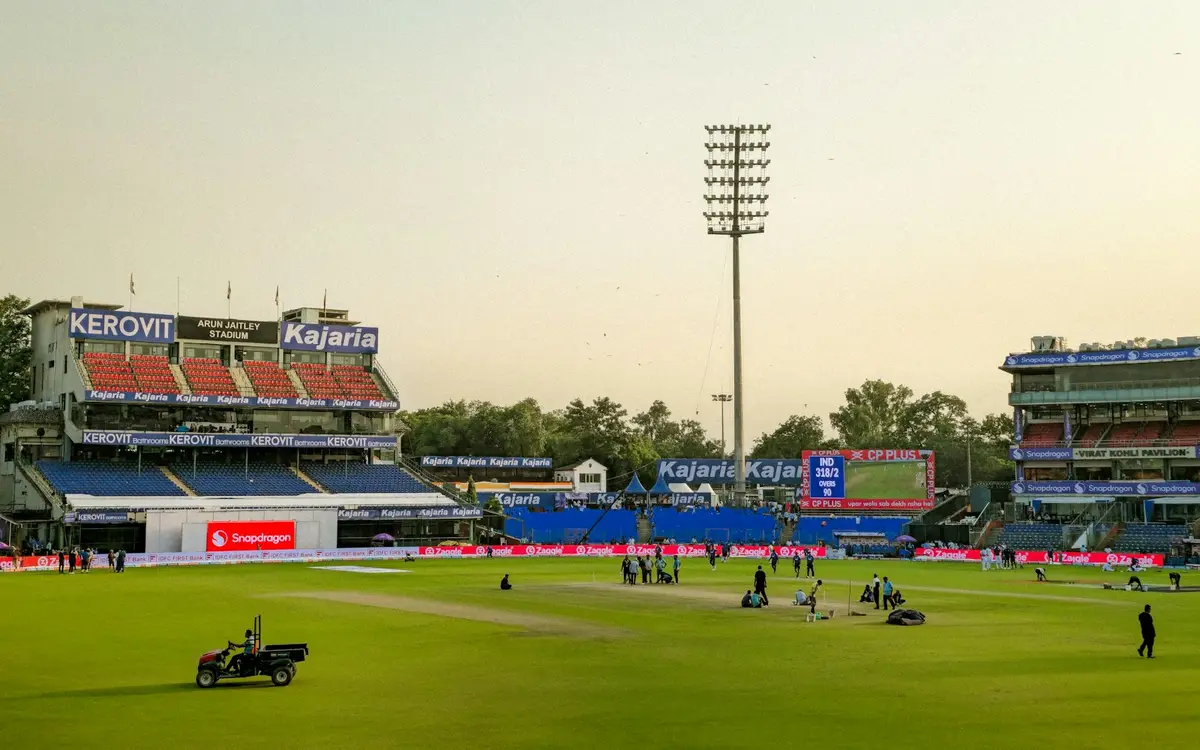 cricket stadium with stands and field under bright sky, backdrop for cricket puns in english