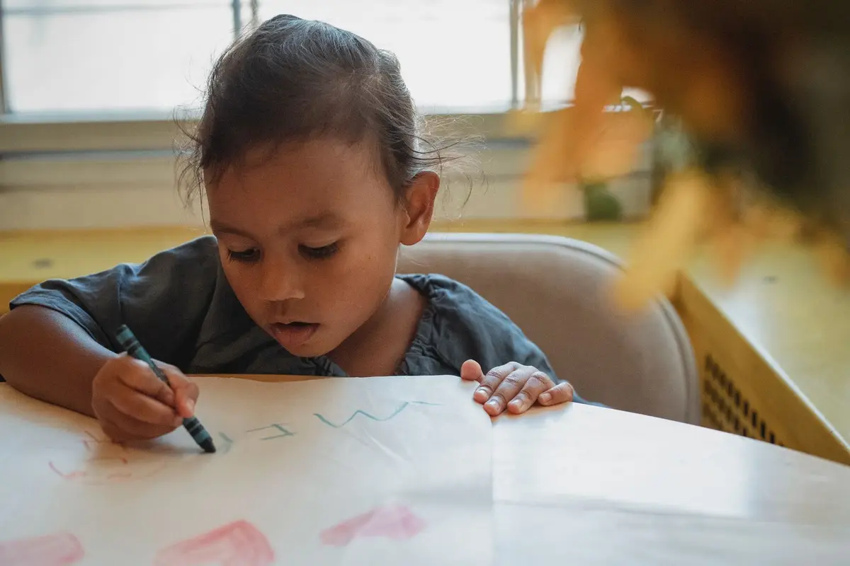young girl drawing with crayons at a table, easy cute pun drawings for kids