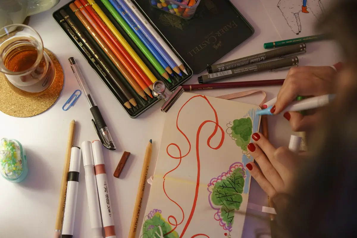 sketchbook doodling session with colored pencils and markers, visual pun art supplies