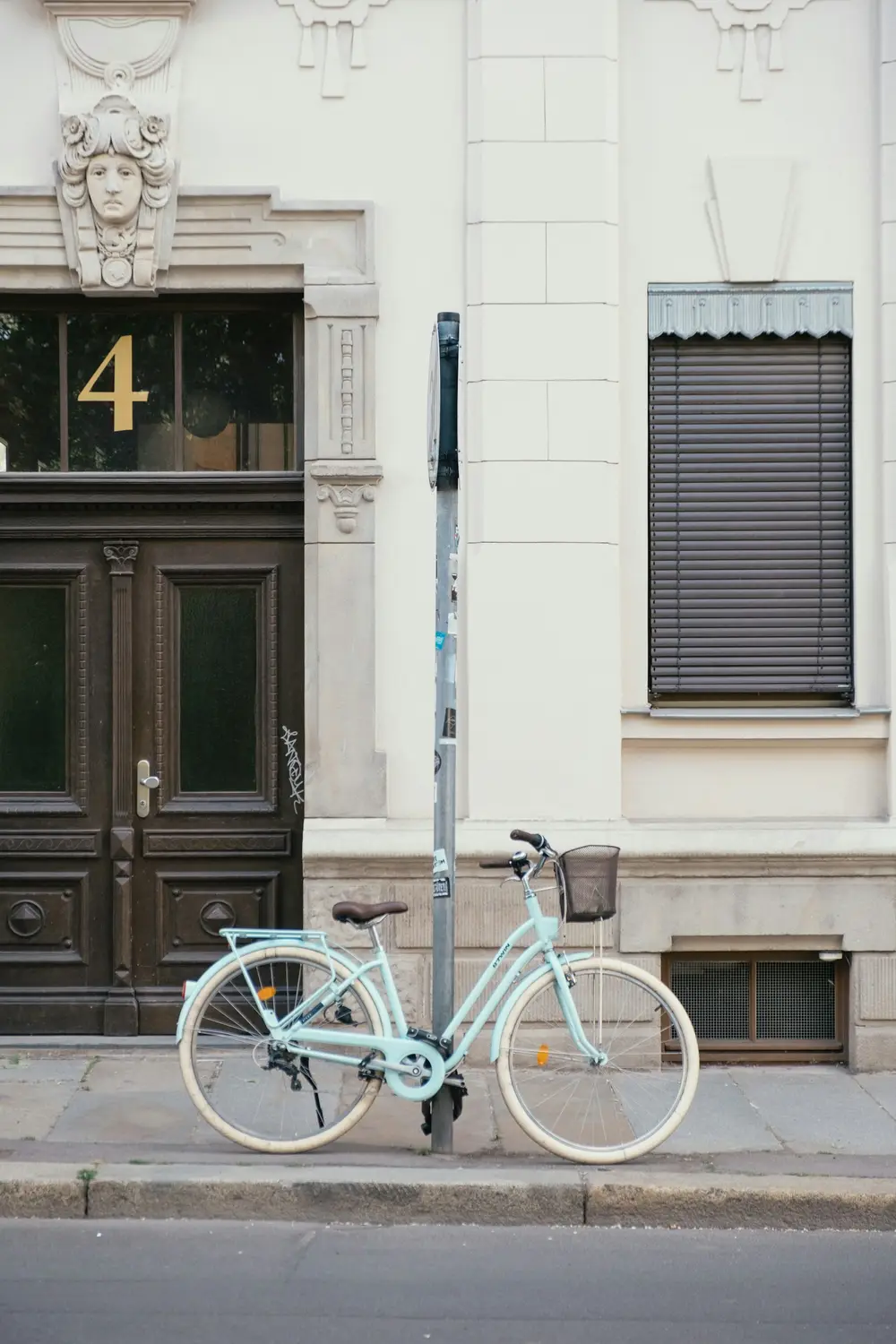 mint green city bicycle with a basket parked beside a wooden doorway, image for short bicycle puns