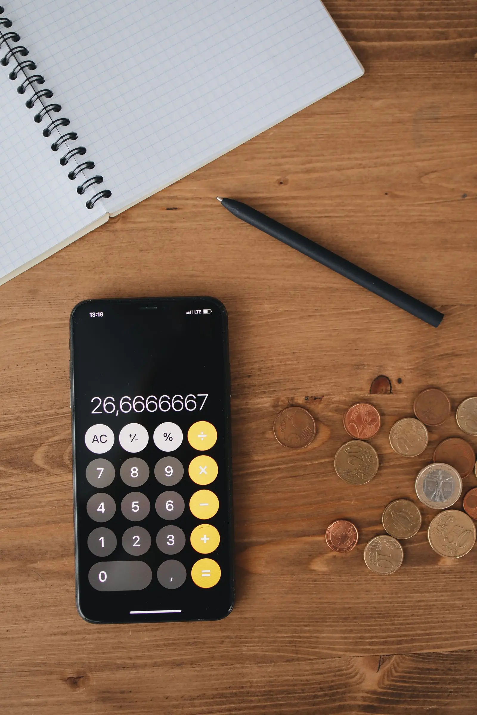 notebook and pen beside a calculator on a wooden table, image for clean math dad jokes about homework