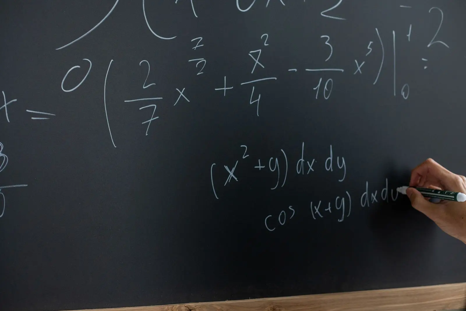 hand writing a mathematical equation on a blackboard, image for arithmetic dad jokes about math