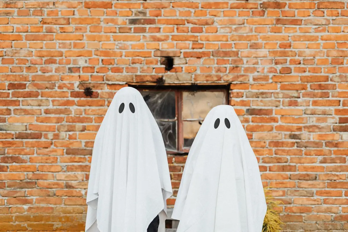 two people in white sheet ghost costumes against a brick wall, ghost jokes