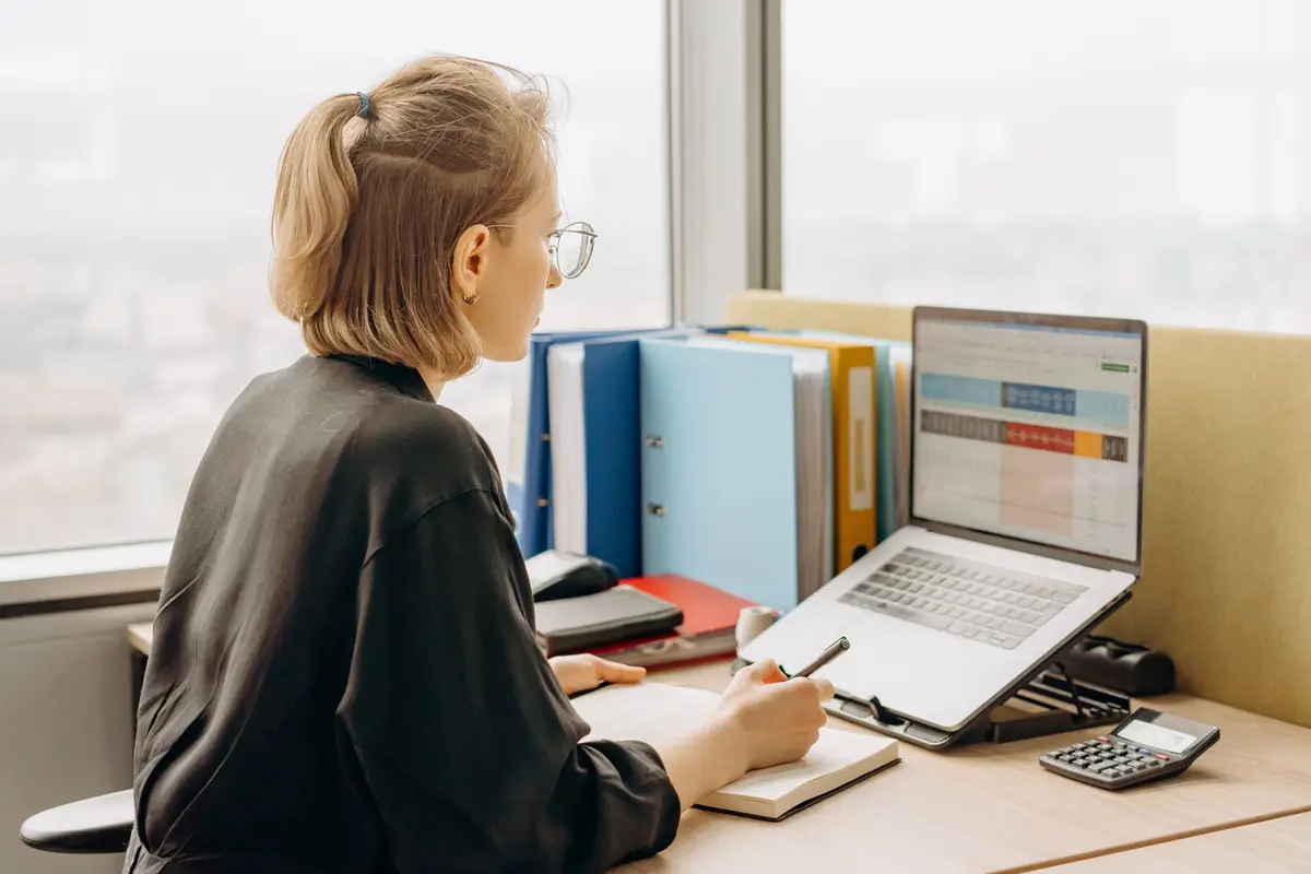 woman working on a laptop with spreadsheets in a modern office, excel jokes and spreadsheet puns