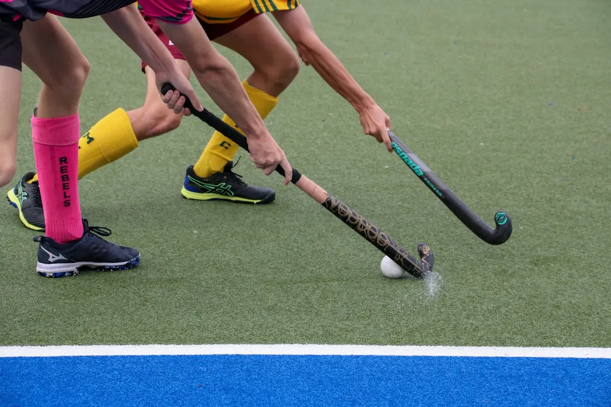 field hockey players chasing the ball on a grass pitch, image for field hockey puns