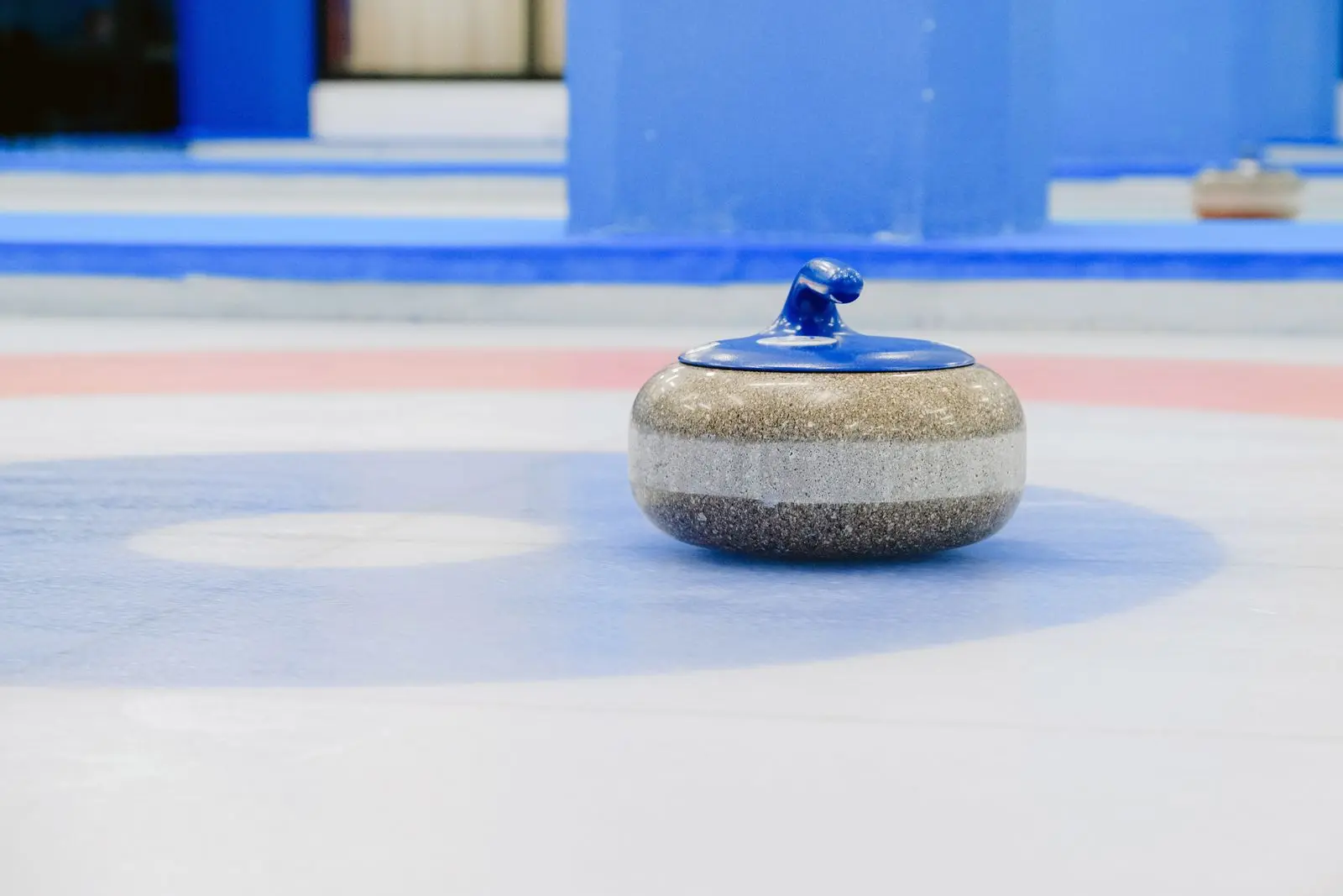 close-up of a curling stone on a colorful ice sheet house, image for curling jokes about the house and the button