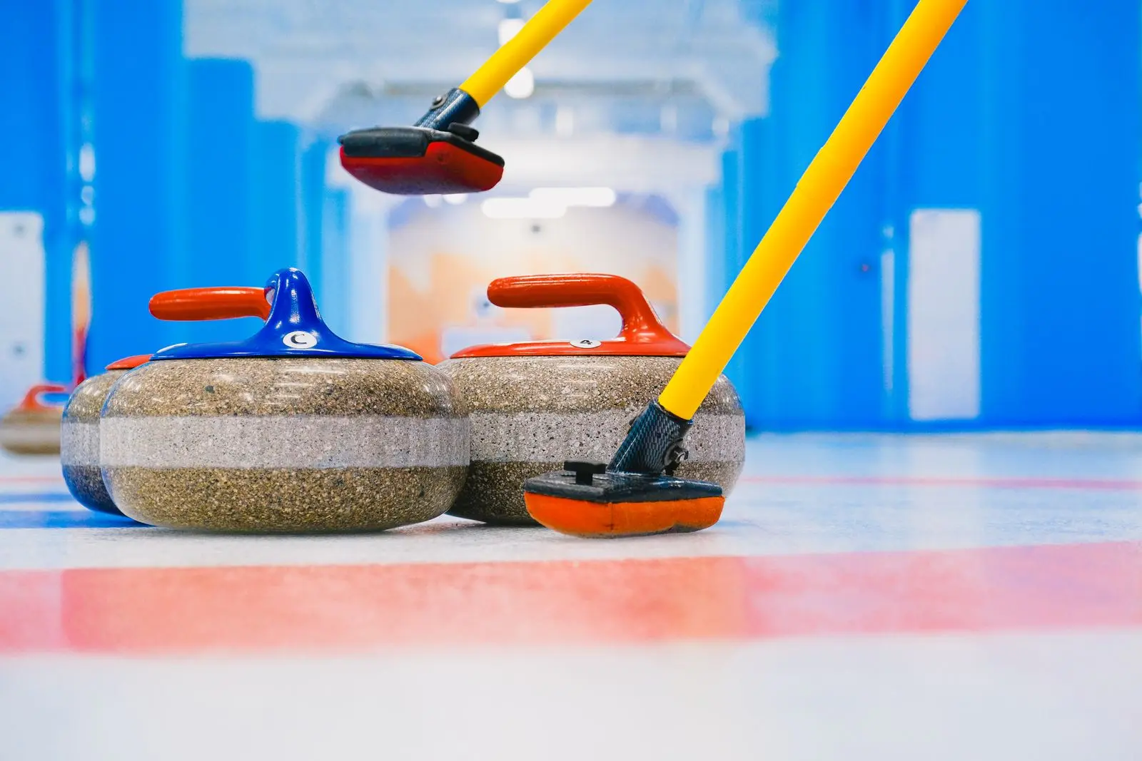 curling stones with brooms in the house on ice, image for curling jokes about the stone and the hammer