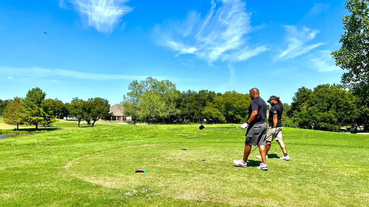 two golfers walking across a sunny fairway under a blue sky, image for funny golf one-liners about the fairway