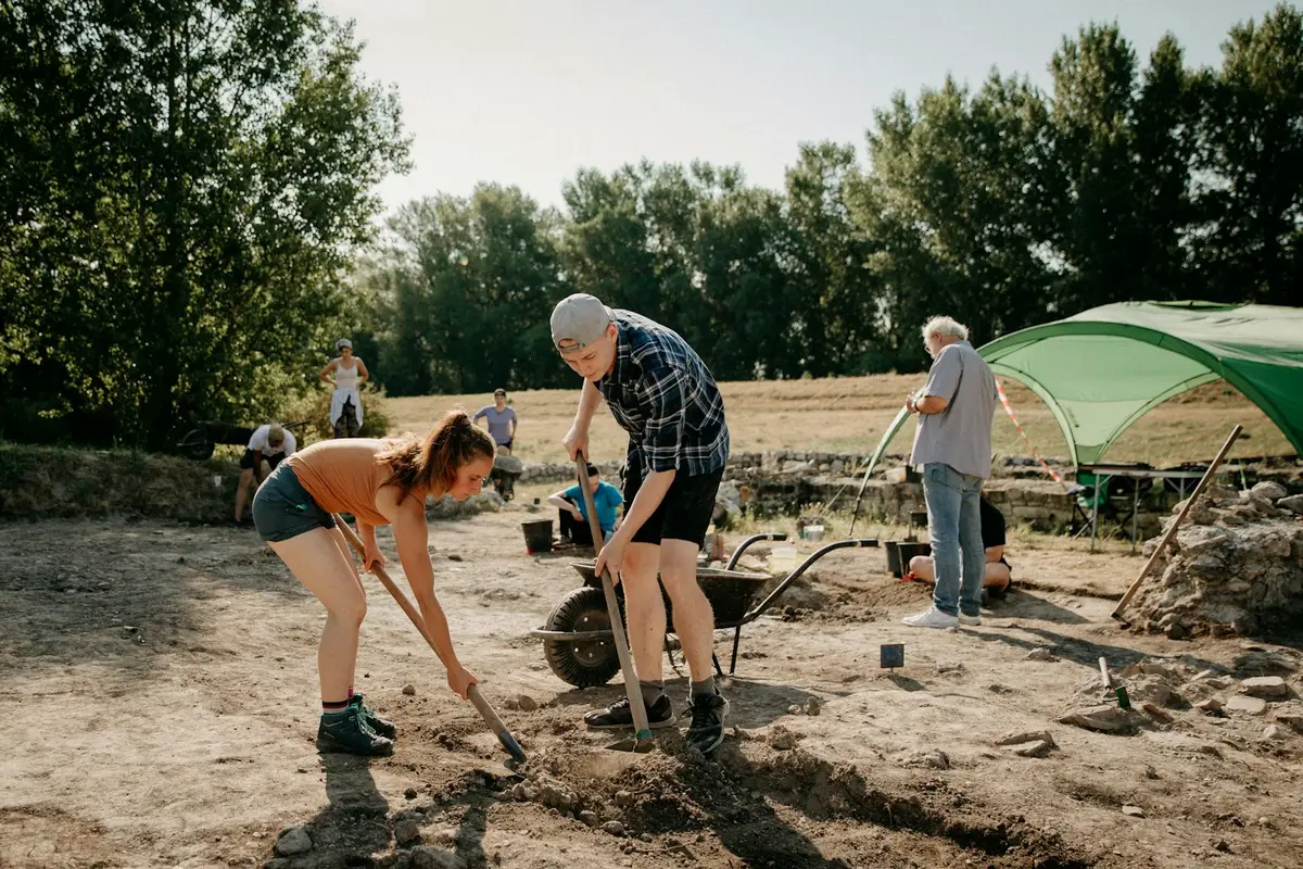 a group of archaeologists carefully excavating a dig site outdoors, image for archaeology history puns
