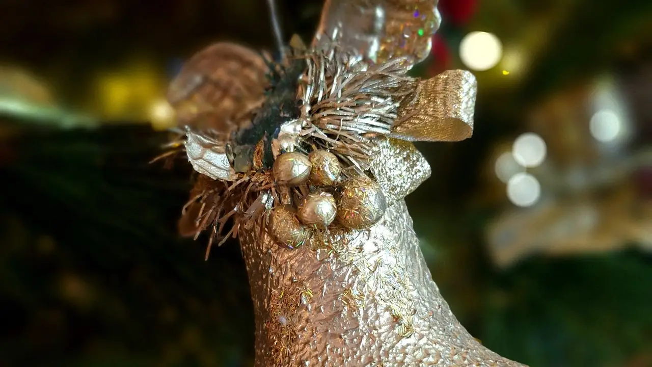 a gold glittered jingle bell ornament on a Christmas tree, image for classic jingle bell puns