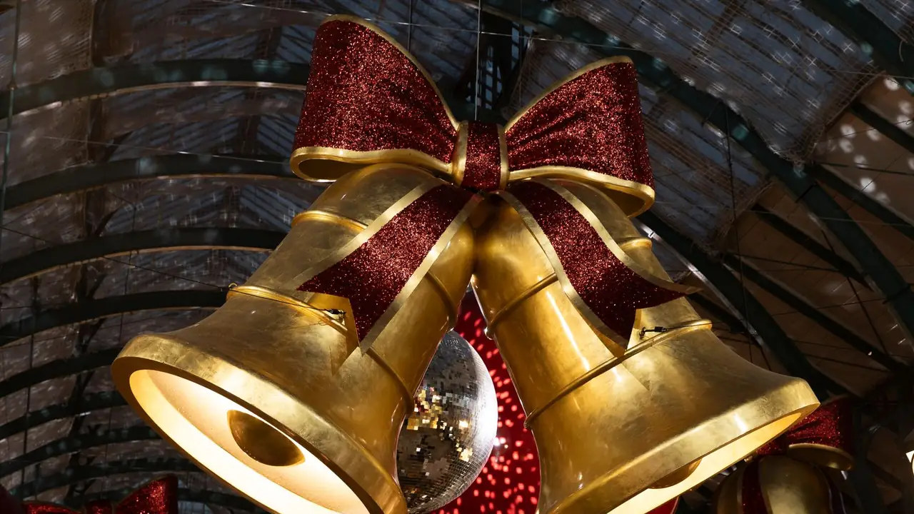 two gold bells with a red bow at a Christmas market, image for sleigh bell puns