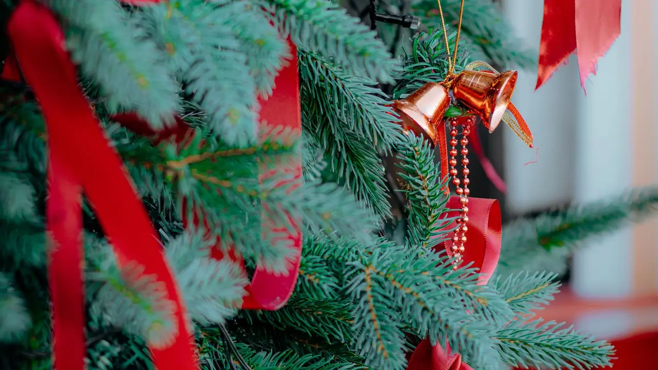 red ribbon and bells on a decorated pine tree, image for jingle bell gift tag and card captions