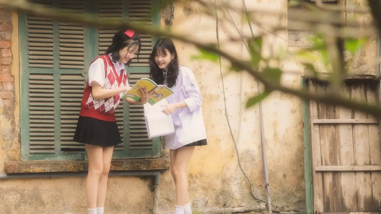 two students sharing an open book outdoors, image for funny jokes for teens about school