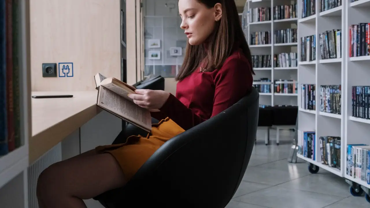 a young reader holding an open book in a library chair, image for joke book for teenagers book and library jokes