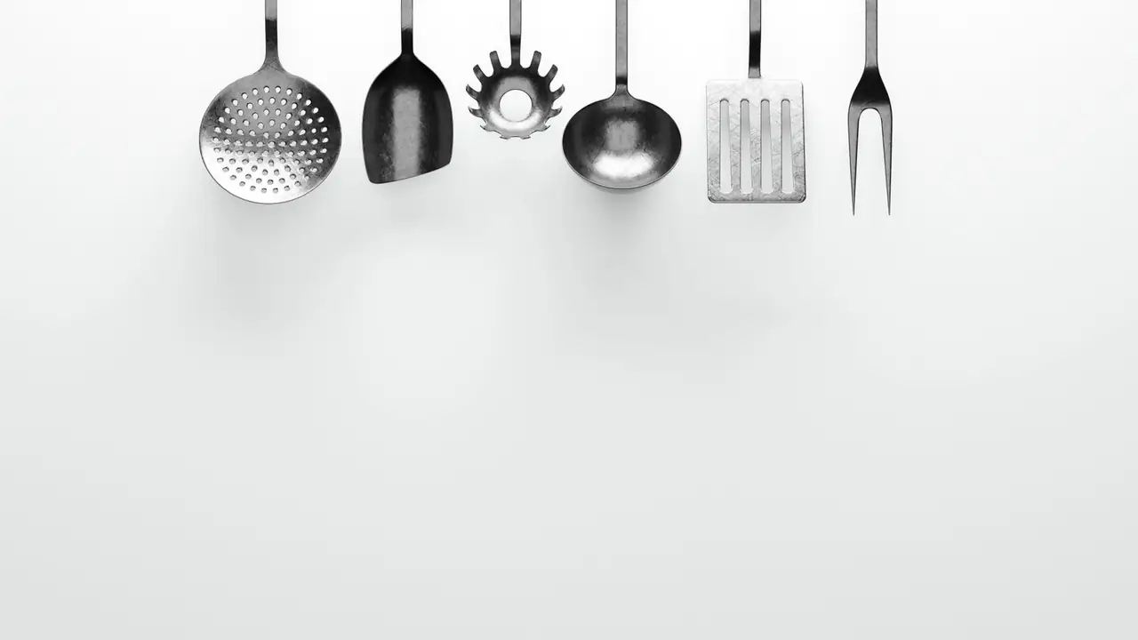 stainless steel kitchen utensils hanging on a rail above a stove, image for cooking utensil puns