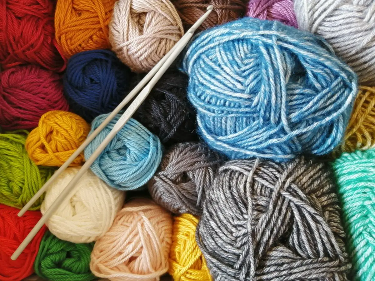 knitting needles with orange, blue and white yarn mid-project, image for knitting needle puns