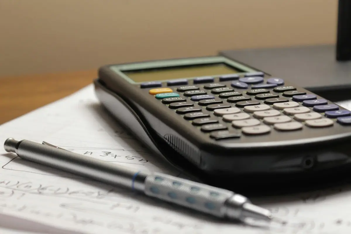 calculator and pen resting on paper, image for everyday math puns about money, time and cooking