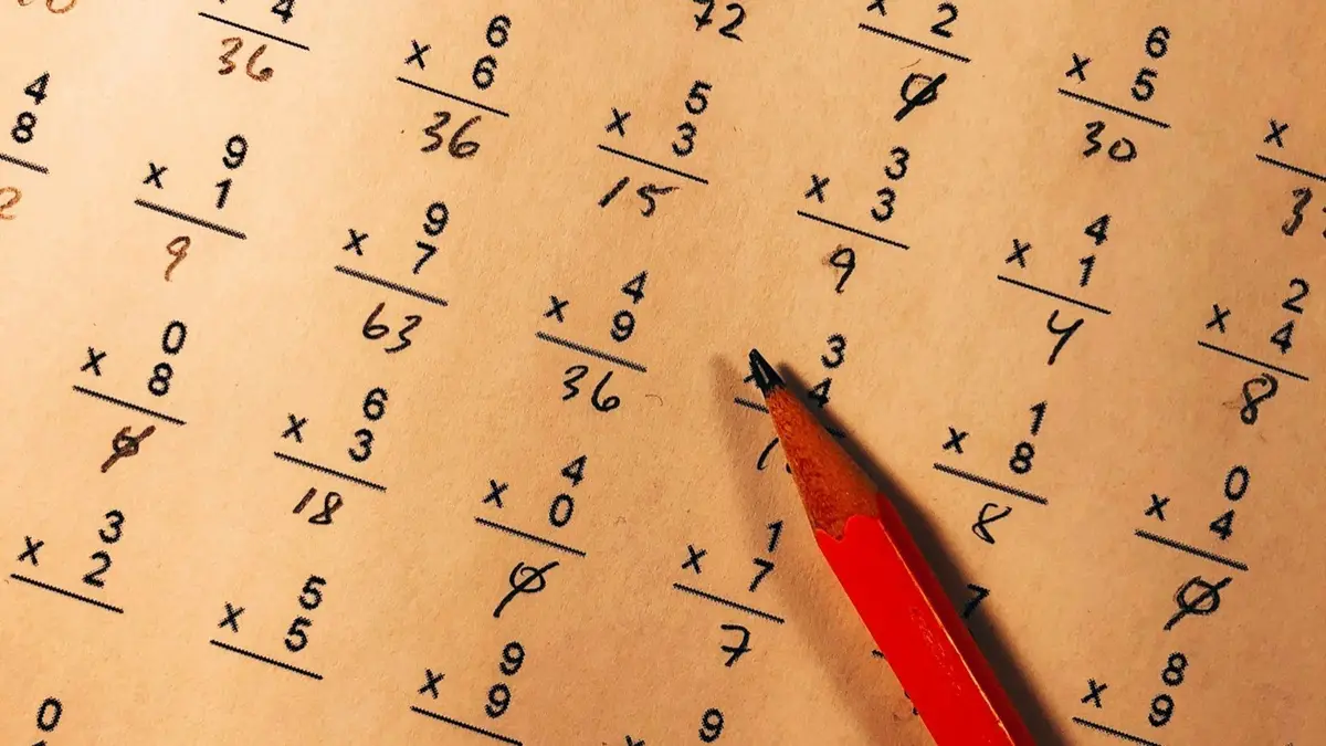 red pencil on a multiplication worksheet, a classroom scene for math puns for kids and teachers