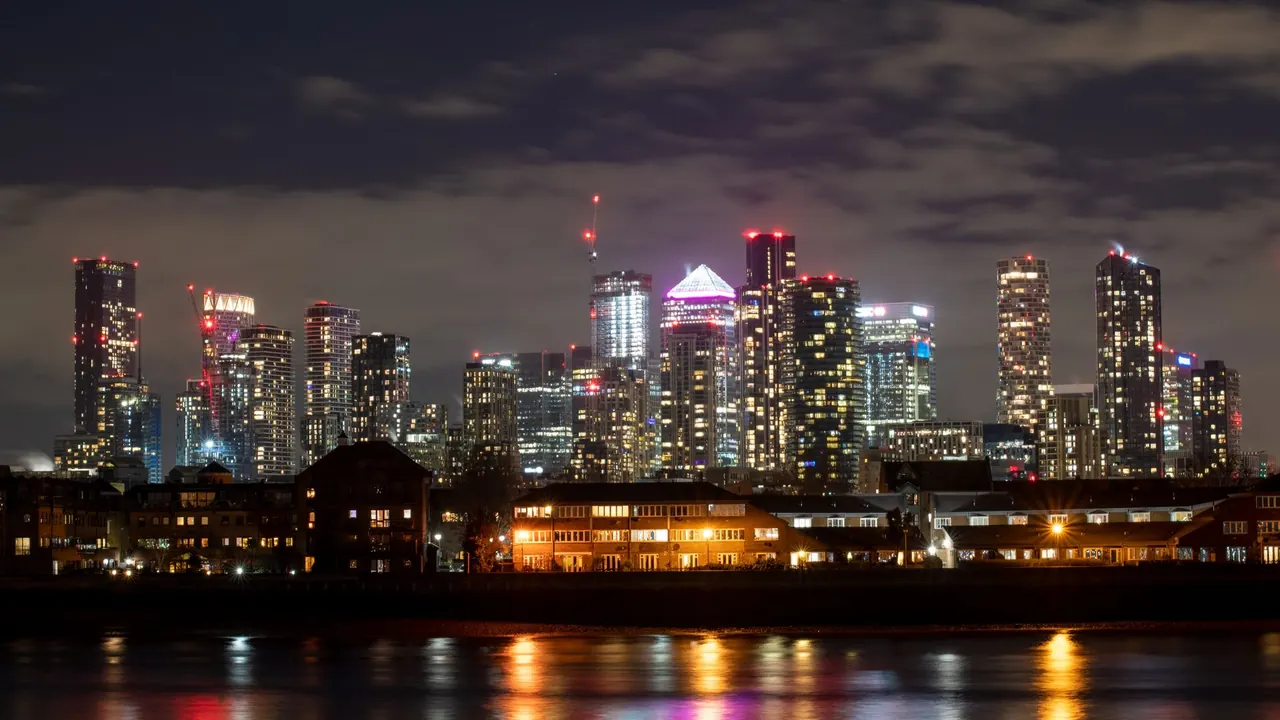 the canary wharf skyline lit up at night across the thames, image for millwall docklands derby jokes