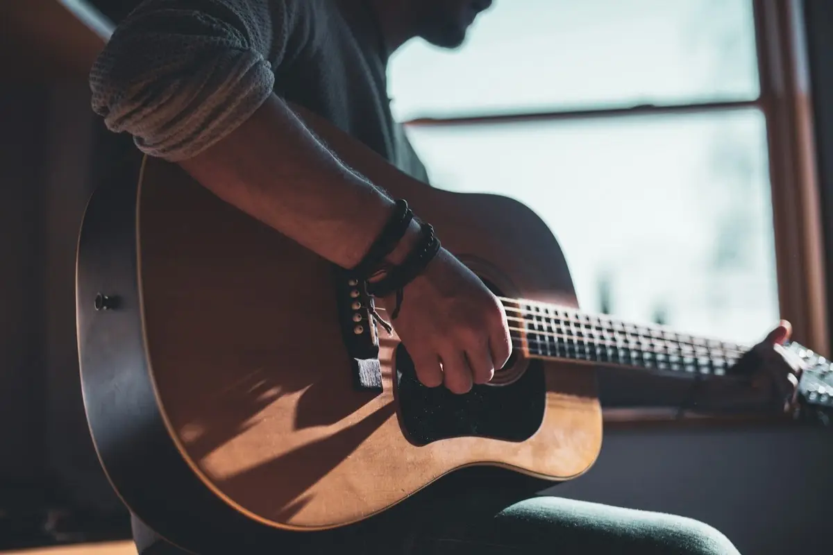 man playing an acoustic guitar, inspiration for guitar puns and band puns