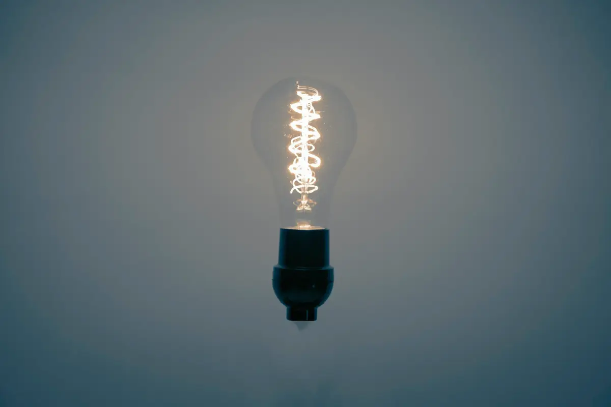 a glowing incandescent lightbulb against a dark background, image for energy and thermodynamics physics puns