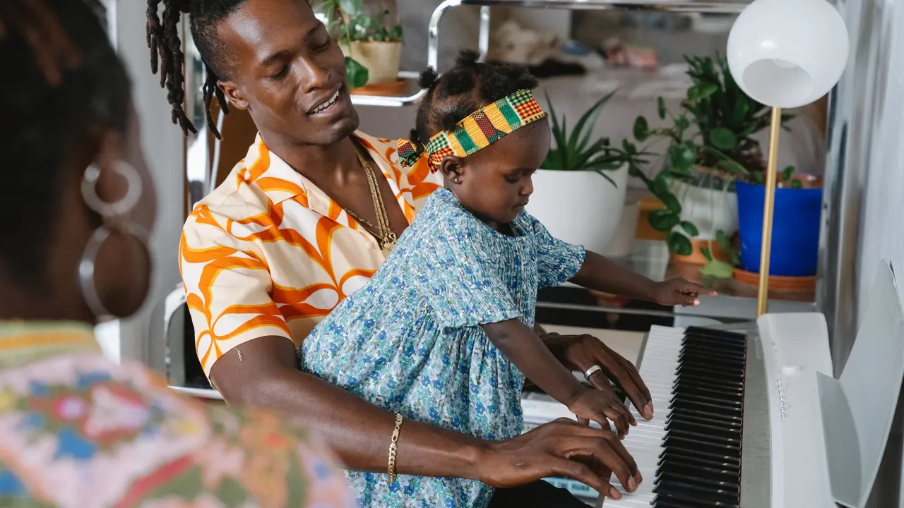 a father and daughter sitting together at a piano, image for piano duet jokes