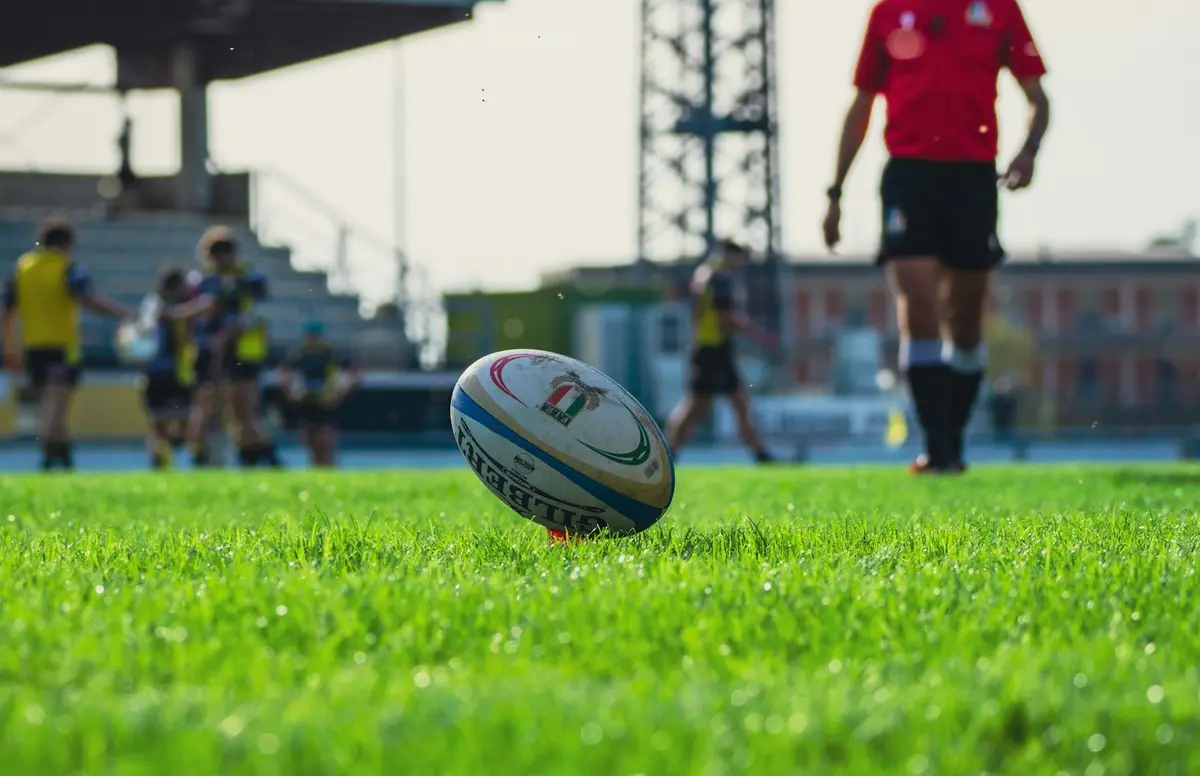rugby ball sitting on a lush green pitch, backdrop for rugby puns for instagram