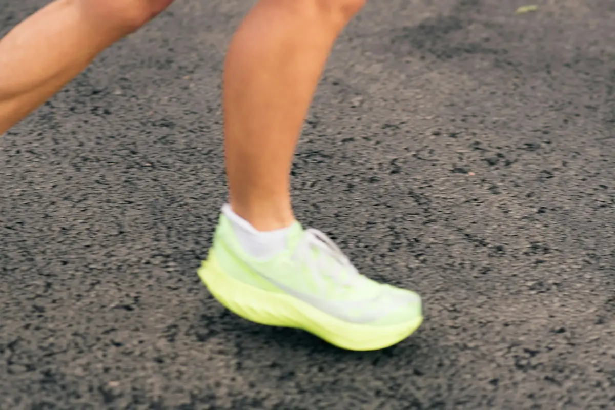 neon green running shoe mid-stride on asphalt, image for running shoe puns