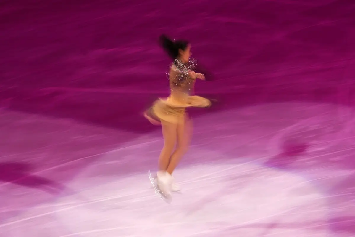 figure skater in a gold dress spinning on a rink lit in pink, image for figure skating puns