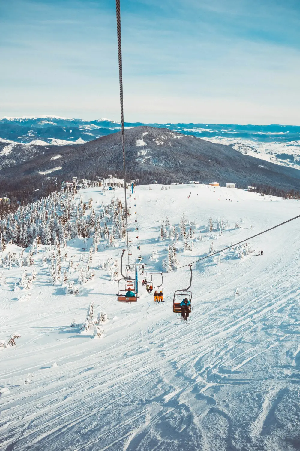 view from a chairlift over a snowy ski resort and mountains, scene for ski trip and lift ticket puns