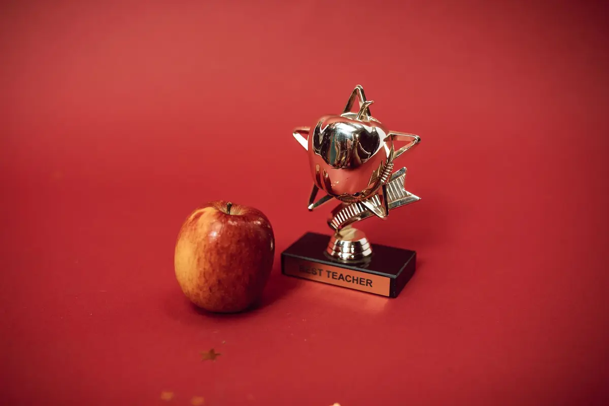 red apple beside a best teacher trophy, soda puns for teacher appreciation week