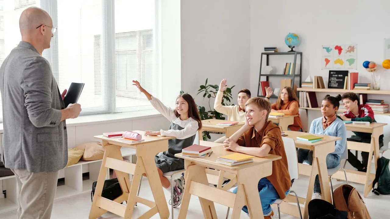 a teacher in front of a bright classroom with students raising hands, image for spanish class jokes