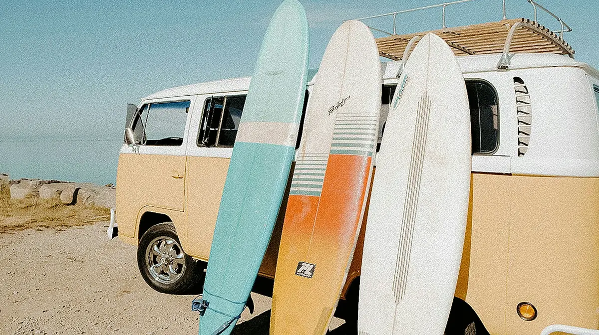 surfboards leaning against a vintage van parked by the beach, image for surfing sayings