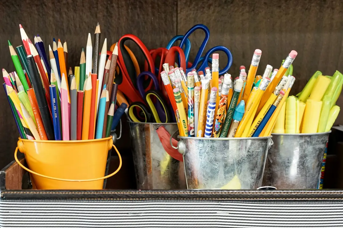 pencils and scissors in yellow and metal buckets, scene for teacher puns about classroom supplies