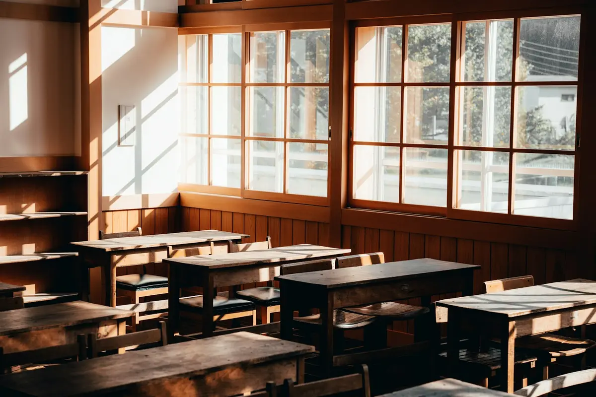 sunlit classroom with wooden desks and tall windows, image for funny teacher puns