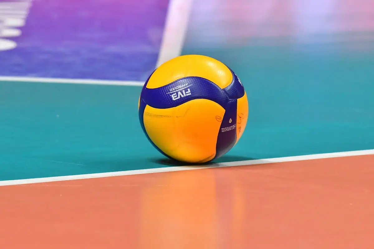 volleyball resting on a colorful indoor court floor, scene for volleyball terms puns