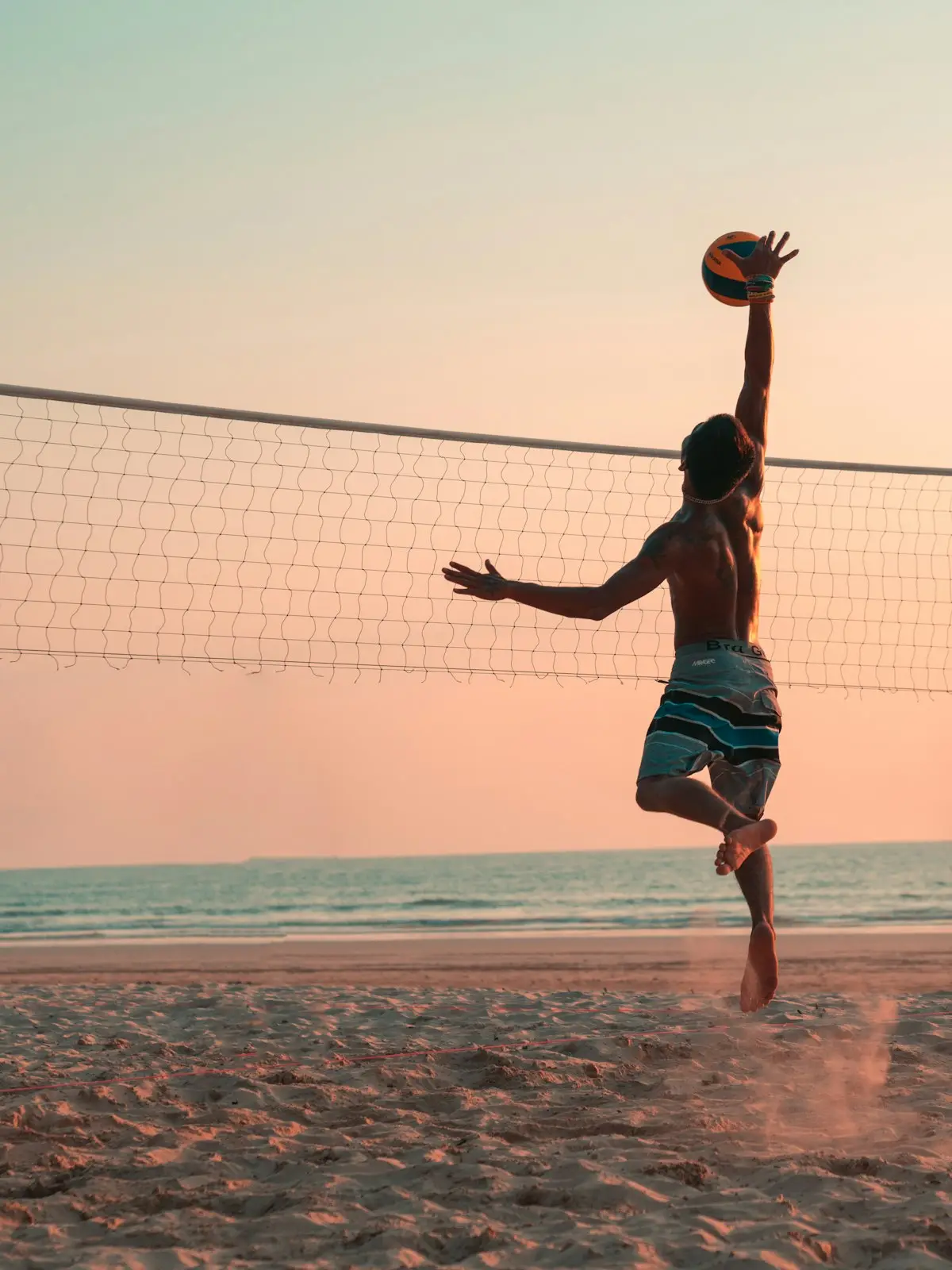 beach volleyball player leaping to spike the ball over the net, scene for volleyball puns one liners