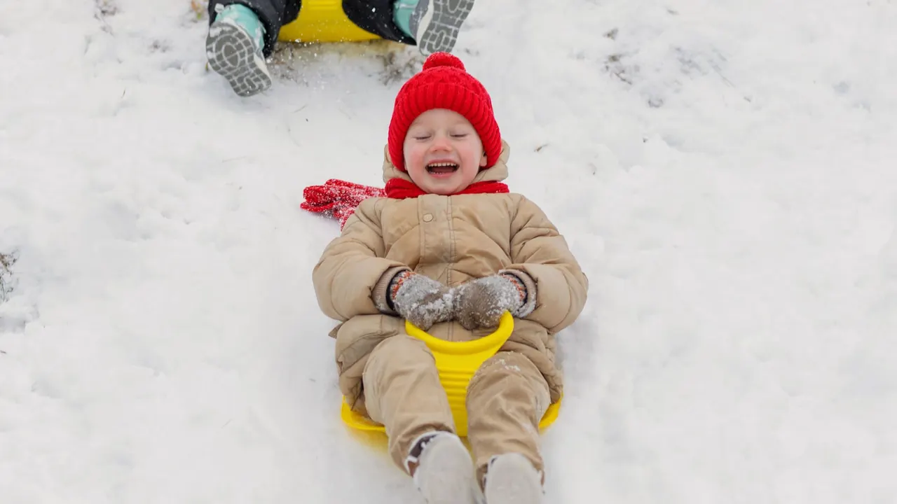 two children sliding down a snowy hill on sleds, image for sledding puns