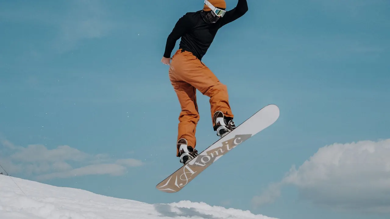 a snowboarder in mid-air against a blue sky, image for snowboarding jokes