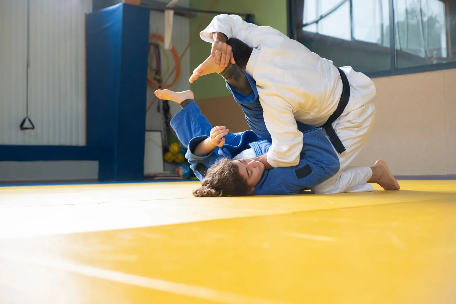 athletes training on a yellow tatami mat, image for funny wrestling dad jokes about the mat