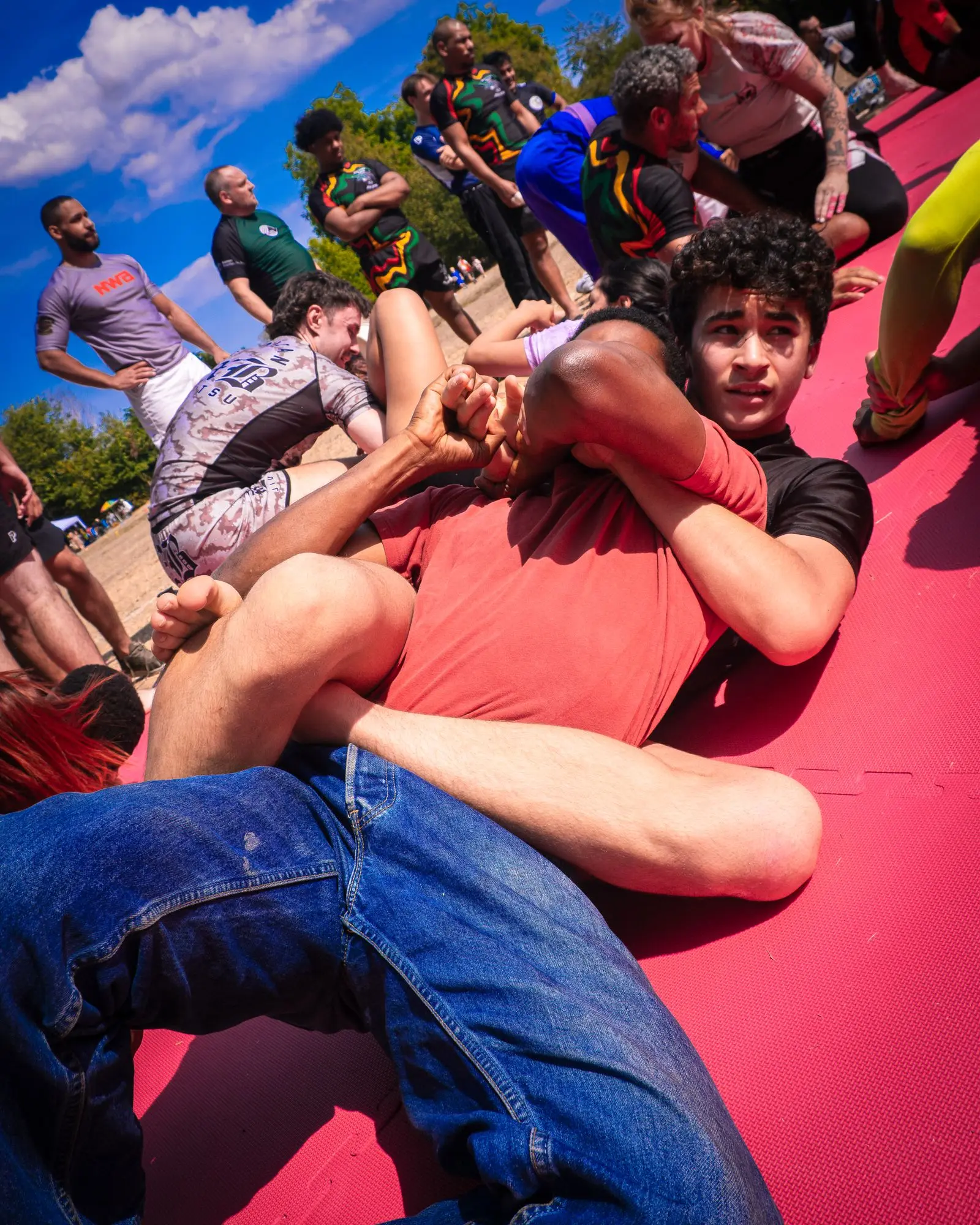 outdoor grappling practice on a red mat, image for high school wrestling dad jokes